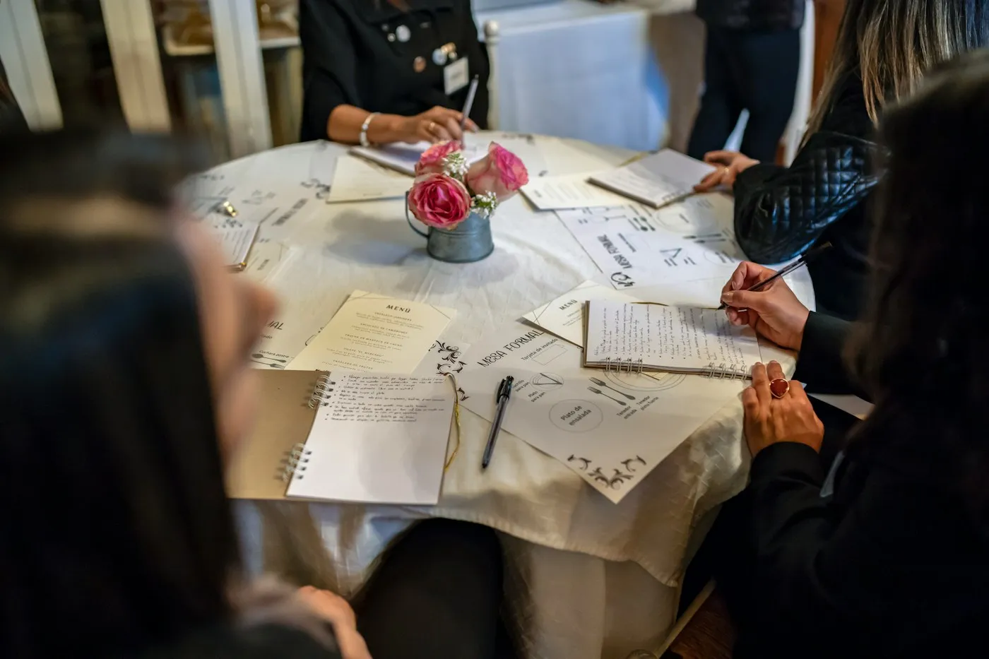 Mesa de trabajo con libretas y flores durante la planificación de un evento