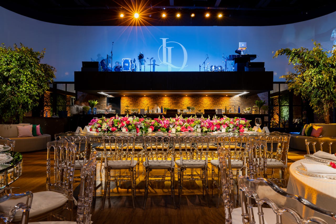 A beautifully decorated wedding venue featuring lush floral arrangements, stylish seating, and dramatic lighting.