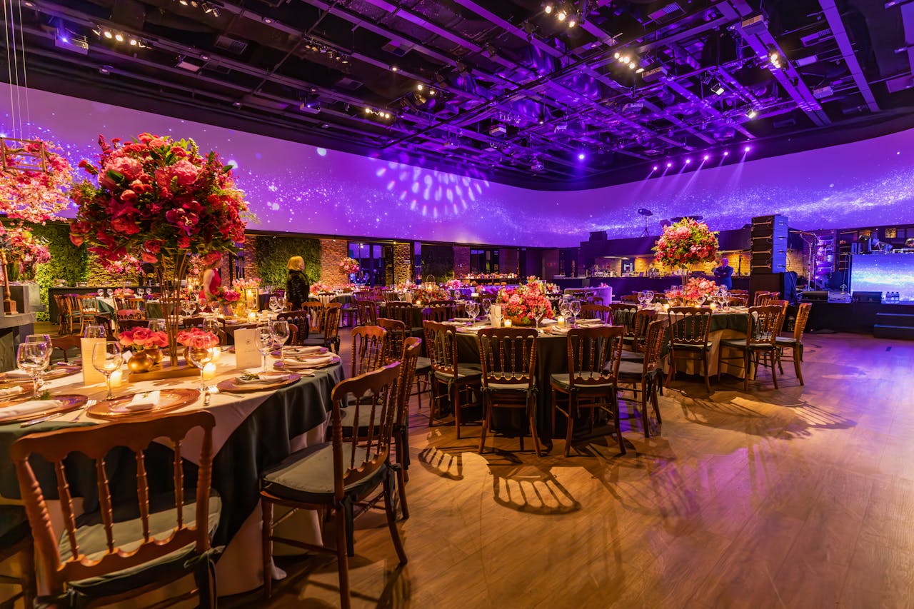 Lavishly decorated event hall with elegant tables and purple lighting, ideal for celebrations.