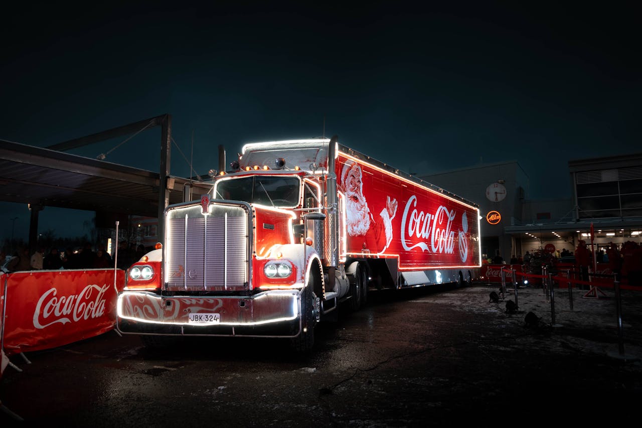 Brightly lit Coca-Cola truck with Santa design, captured at night for holiday festivities.