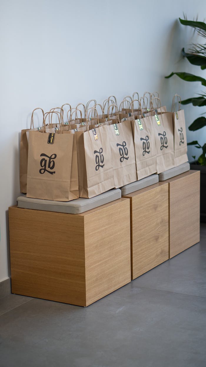 Brown paper gift bags arranged neatly on a modern wooden bench indoors.