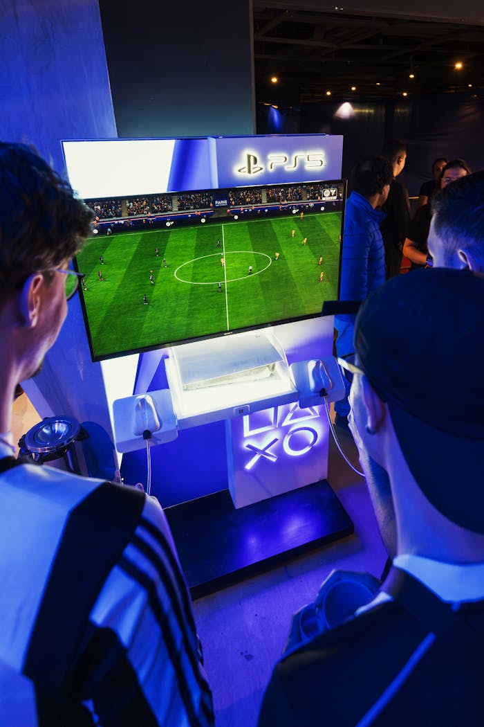 Young adults engaged in a soccer video game on PlayStation 5 in a lively gaming event.