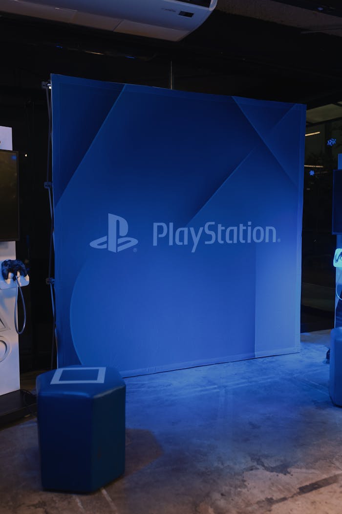 A PlayStation-themed blue backdrop with branding in an indoor setting, illuminated by lights.